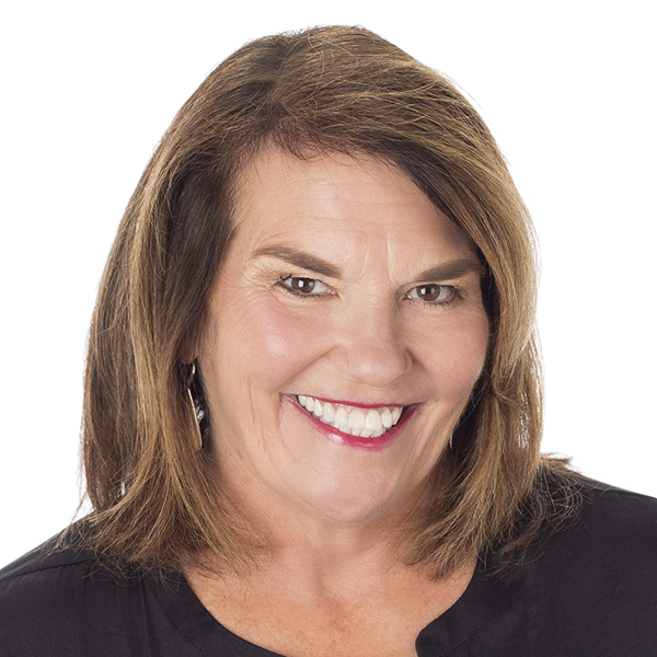 A smiling middle-aged woman with brown hair, wearing a black top, against a white background.