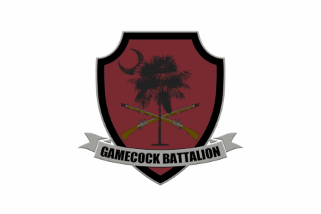A military-style emblem featuring a maroon shield with a palm tree and crescent moon design, crossed muskets at the center, and a banner below that reads 'GAMECOCK BATTALION.'