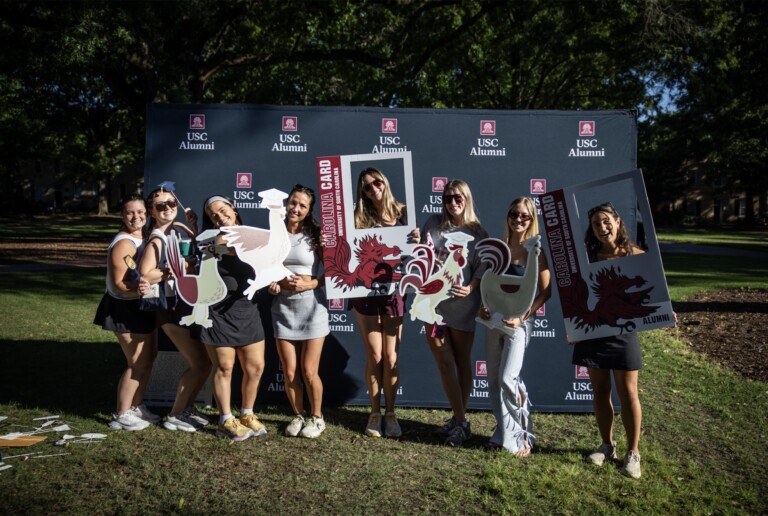 A group of young women posing with large, decorative frames featuring the University of South Carolina logo and themed graphics.