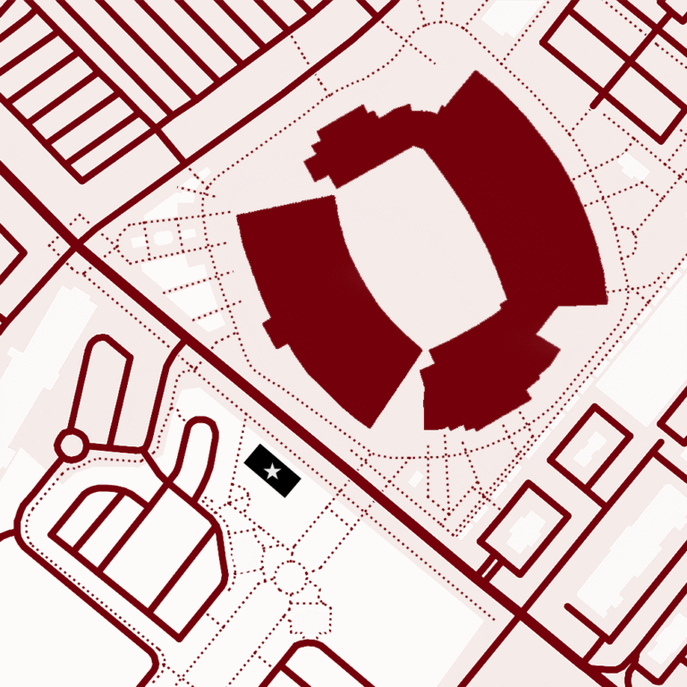 A simplified map showing buildings and roads in a burgundy and beige color scheme, with a prominent structure resembling a stadium or arena.