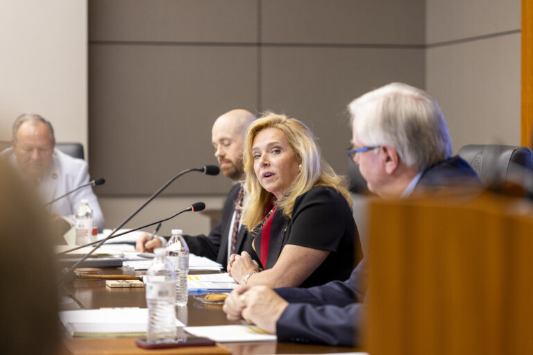 Woman speaking at conference table with three men during professional business meeting
