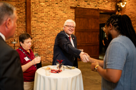 August Reception with USC President Michael Amiridis. Shaking hands at table.